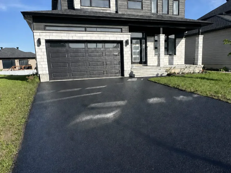 Dark residential driveway in front of a modern two-storey home.