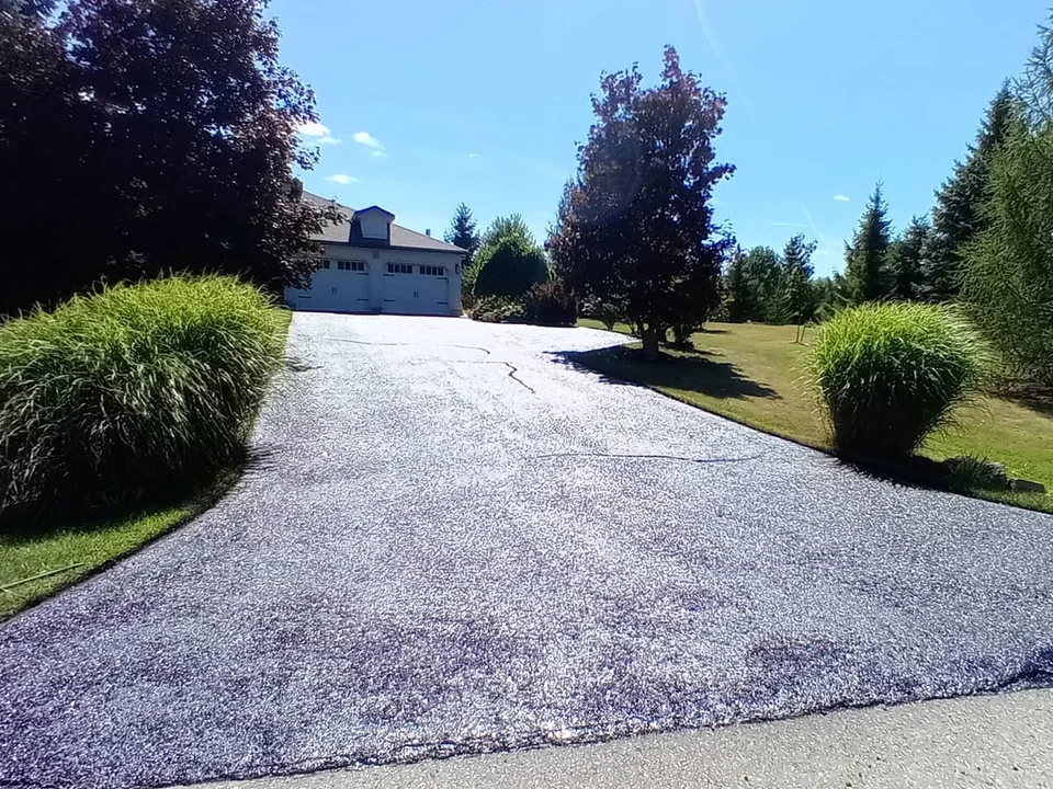 Dark curved driveway leading to a detached home.